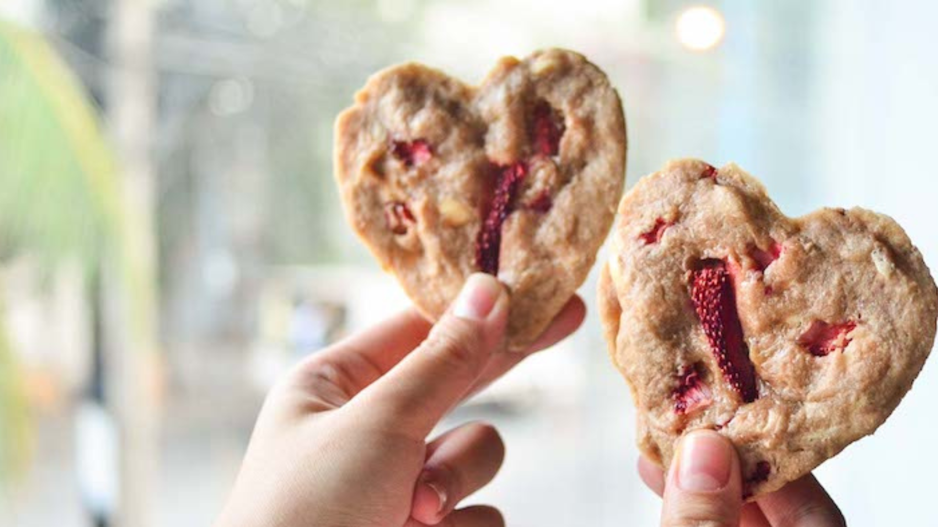A person holding a heartshaped cookies